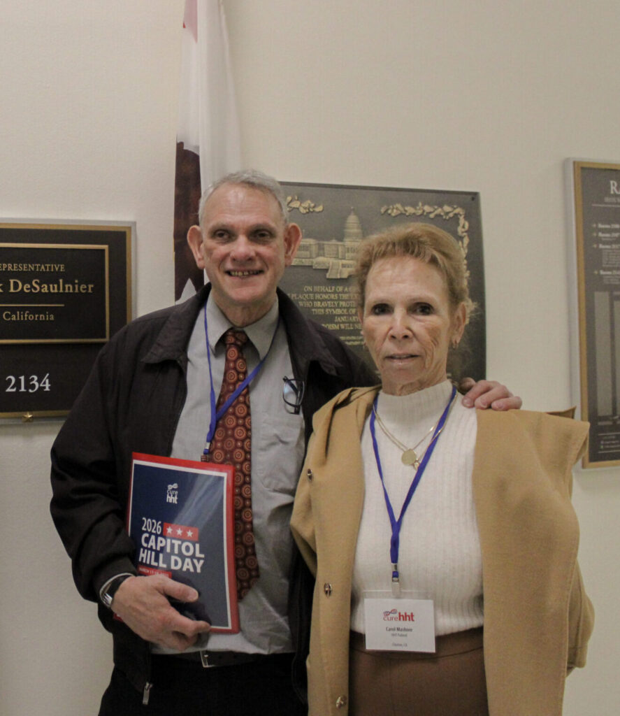 Two people holding a 2026 Capitol Hill Day folder outside a congressional office doorway