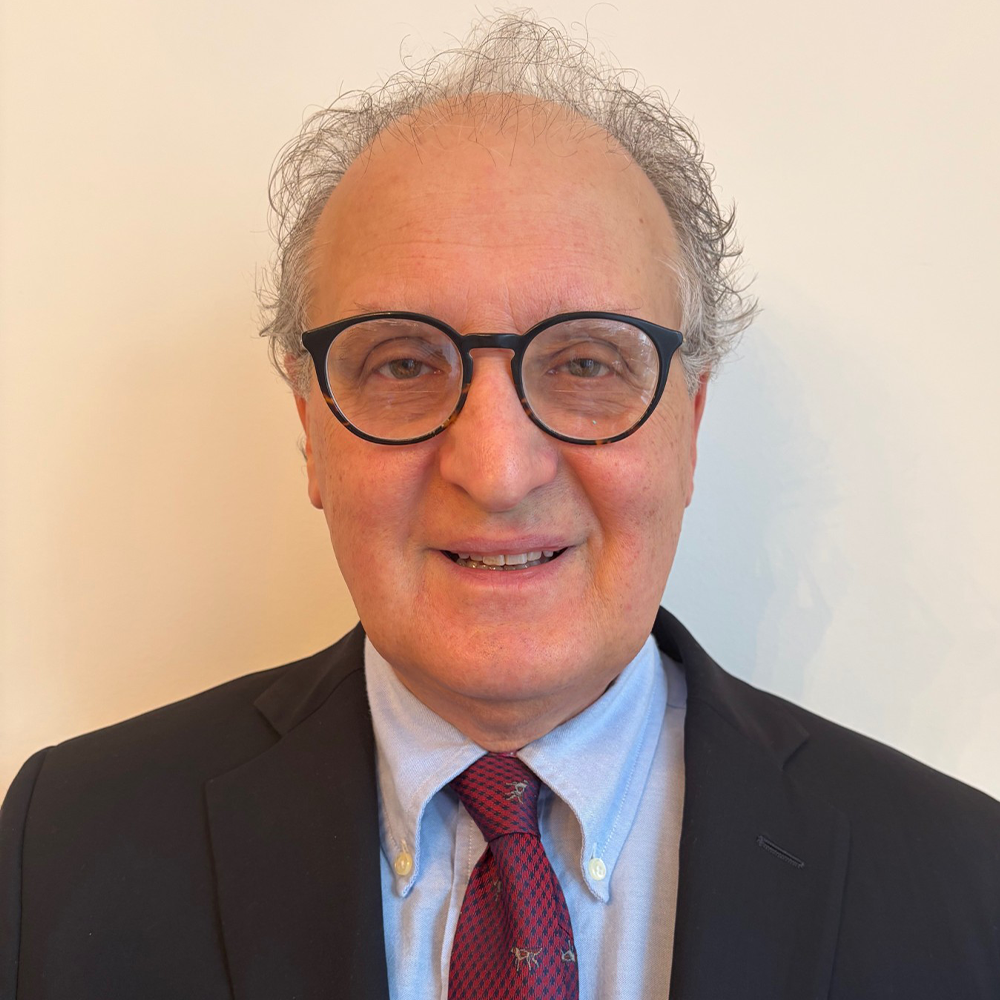 Smiling older man with glasses in a dark suit and red tie
